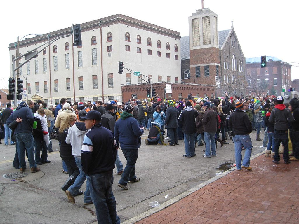 Bundled-up revelers in beads filling a street corner in the Soulard neighborhood during Soulard Mardi Gras in St. Louis