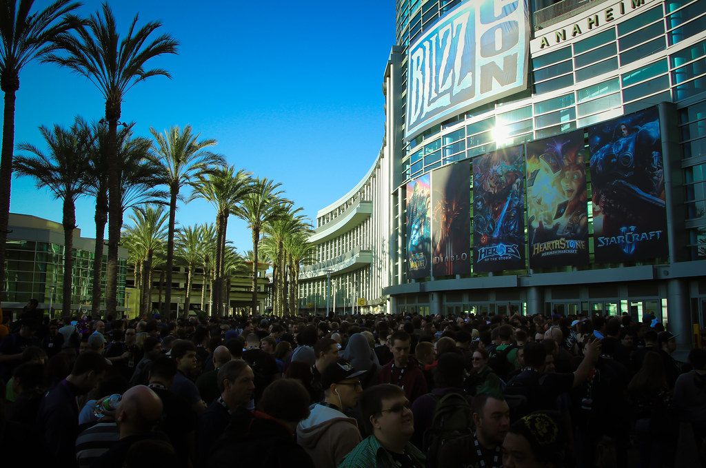 A morning crowd gathered on the palm-lined plaza outside the Anaheim Convention Center under BlizzCon banners and game artwork on the glass facade