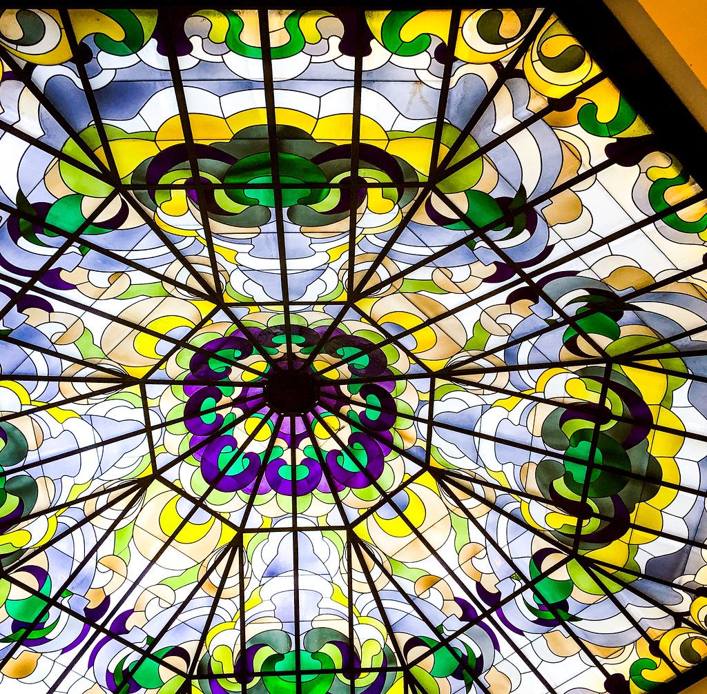 Looking up into an octagonal stained-glass skylight in green, purple and yellow swirls
