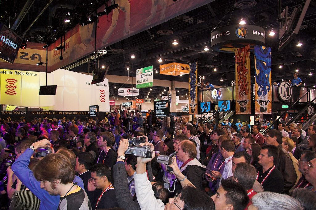 A packed CES 2007 crowd with lanyards and camcorders raised for Honda's Asimo demo at the Las Vegas Convention Center