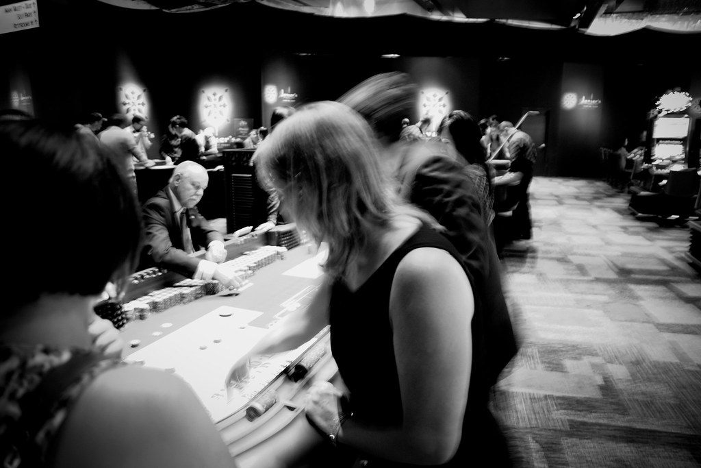 Black-and-white shot of players crowding a craps table late at night in a Las Vegas casino
