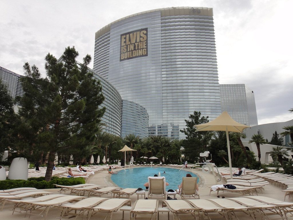 Sunbathers on loungers around the ARIA pool beneath the curved glass hotel tower