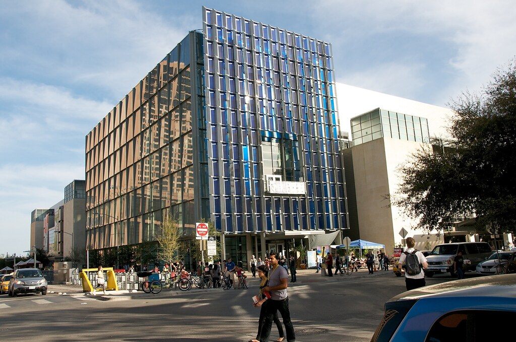 The glass and steel west end of the old Austin Convention Center with people crossing the street in front, 2010
