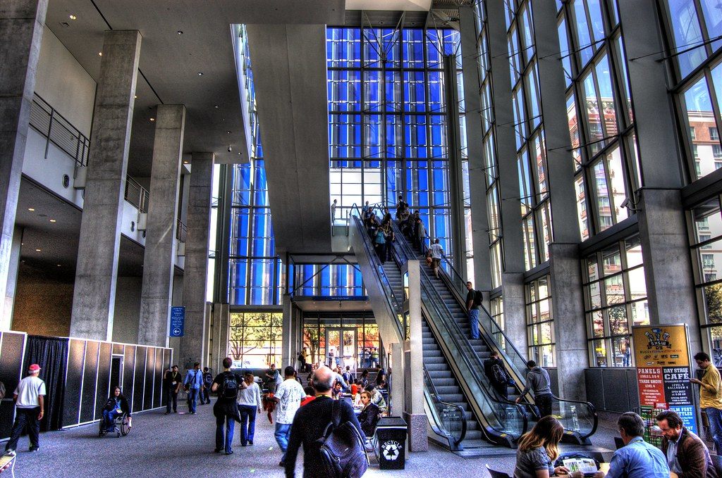 SXSW crowds fill the tall glass lobby and escalators of the old Austin Convention Center