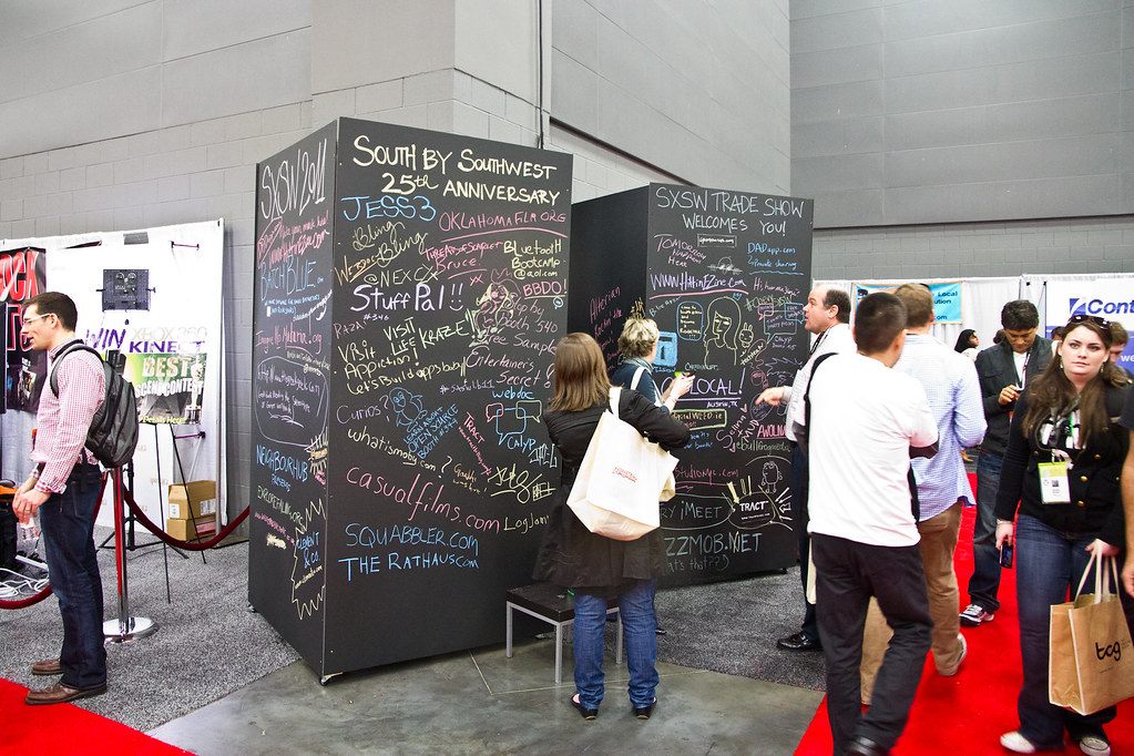 Visitors write on big chalkboard walls marking SXSW's 25th anniversary on the SXSW Trade Show floor