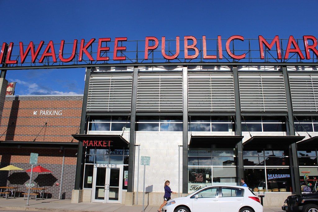 The red neon Milwaukee Public Market sign above the market's glass front in the Third Ward on a sunny day