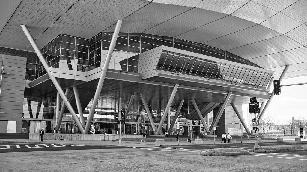Black and white view of the Boston Convention and Exhibition Center entrance, with its sweeping roof canopy held up by angled steel columns over a glass lobby