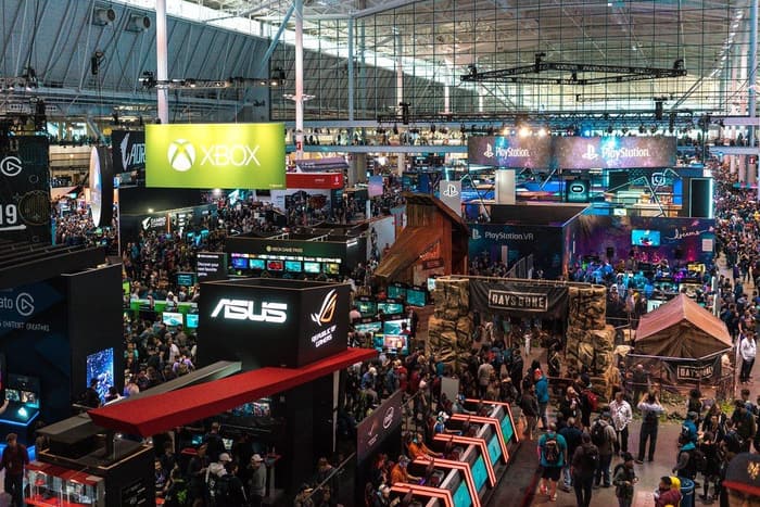 Overhead view of the packed PAX East 2019 show floor at the Boston Convention and Exhibition Center, with Xbox, PlayStation and ASUS booths under the hall's glass and steel roof