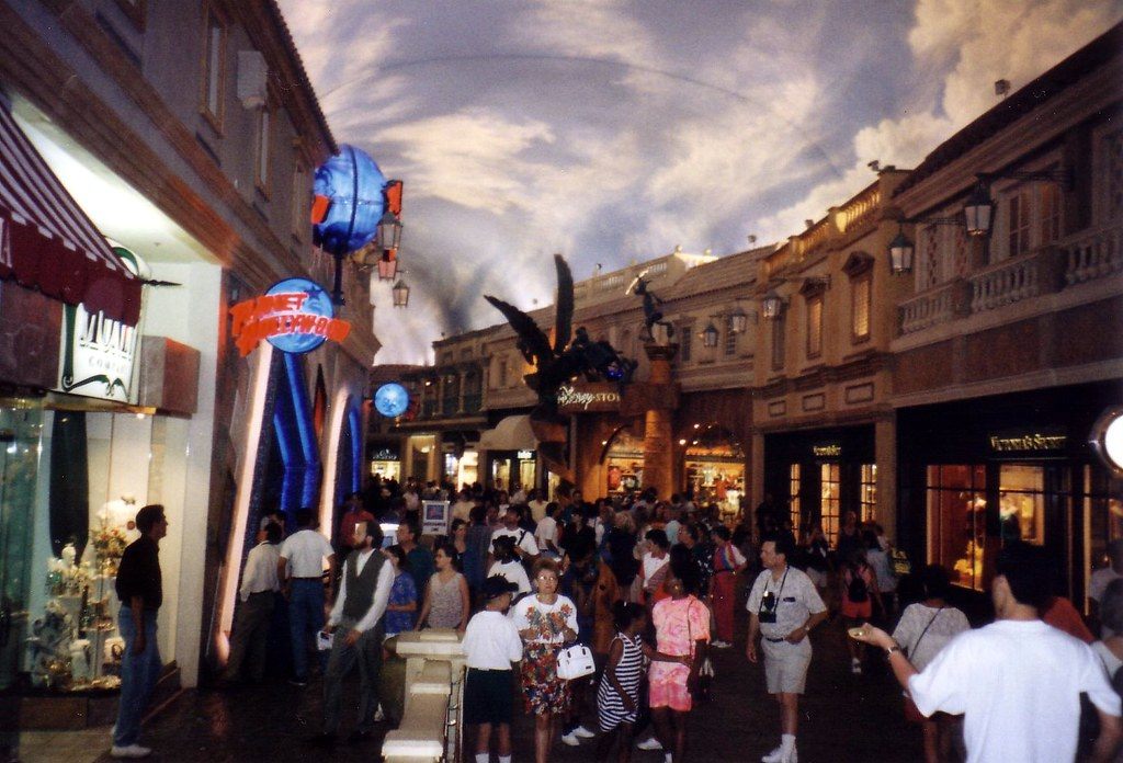 Crowds of shoppers fill a street in The Forum Shops at Caesars Palace beneath its painted-sky ceiling