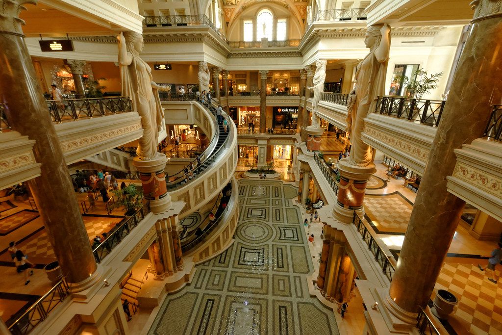 Shoppers riding the spiral escalators and crossing the mosaic floor inside The Forum Shops at Caesars Palace
