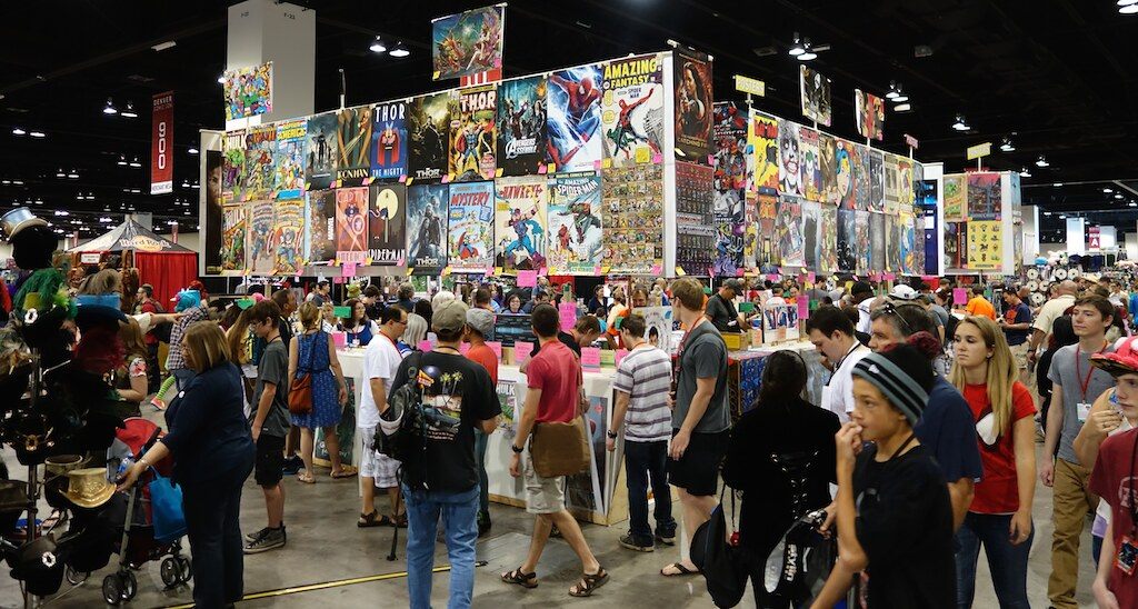 Crowds of fans browse a towering wall of comic books on the show floor at Denver Comic Con 2014