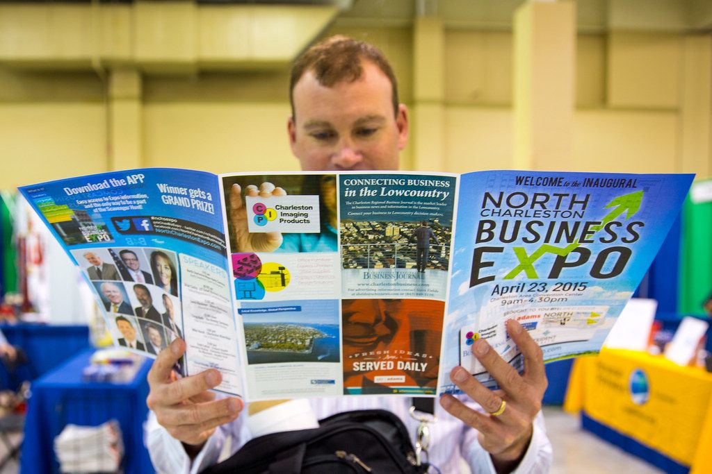 An attendee reads the fold-out program of the inaugural North Charleston Business Expo, April 23, 2015, on the show floor