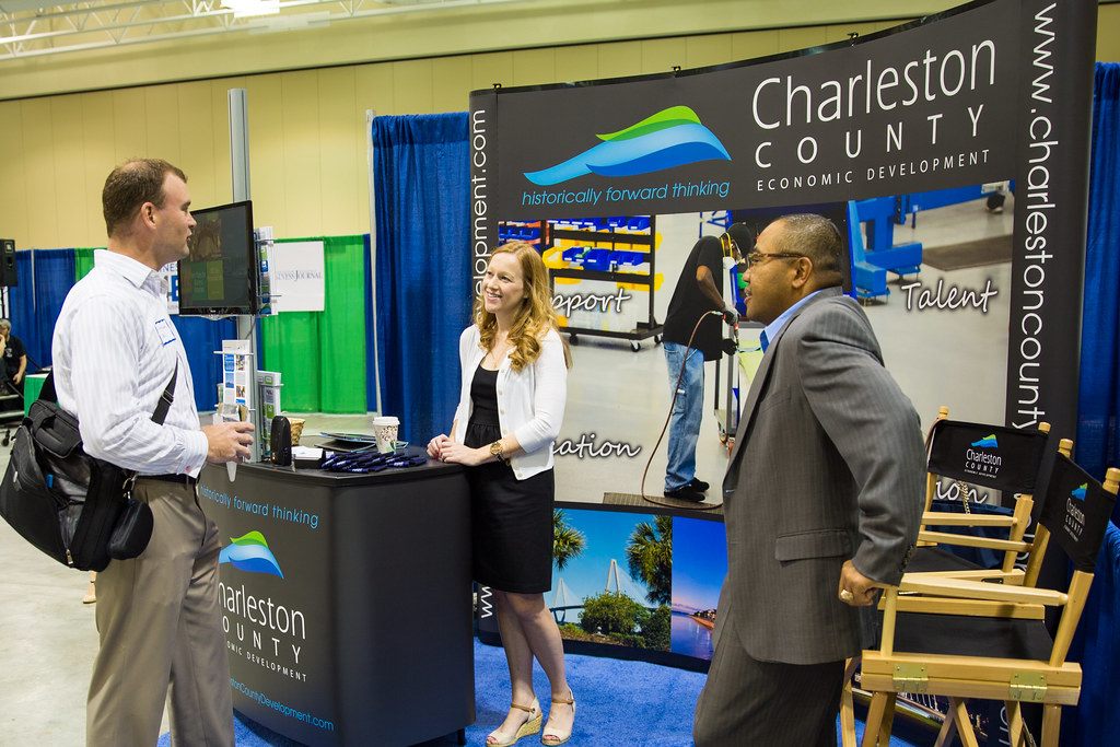 Three people in conversation in front of the Charleston County Economic Development pop-up booth at the North Charleston Business Expo