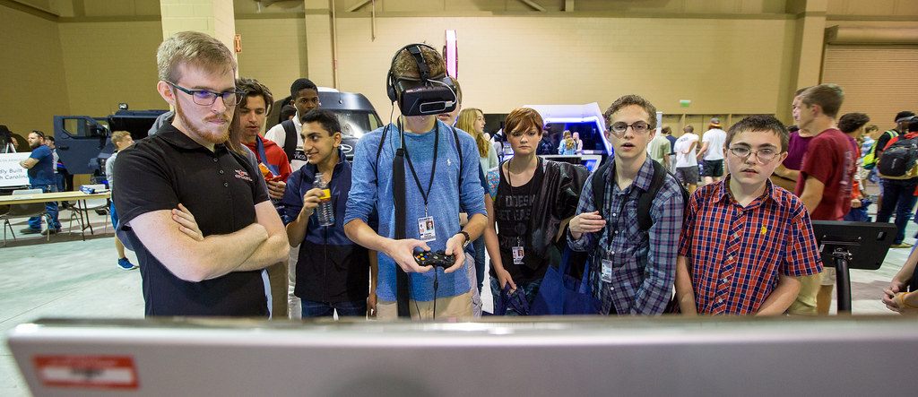 High-school students crowd around a classmate trying a virtual-reality headset at the STEM Career Fair in the Charleston Area Convention Center exhibit hall