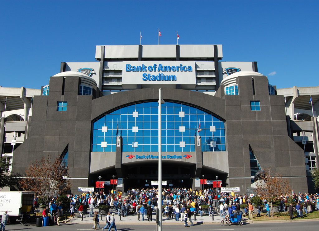 Crowds of Carolina Panthers fans gathering at the main gate of Bank of America Stadium on a sunny game day in uptown Charlotte