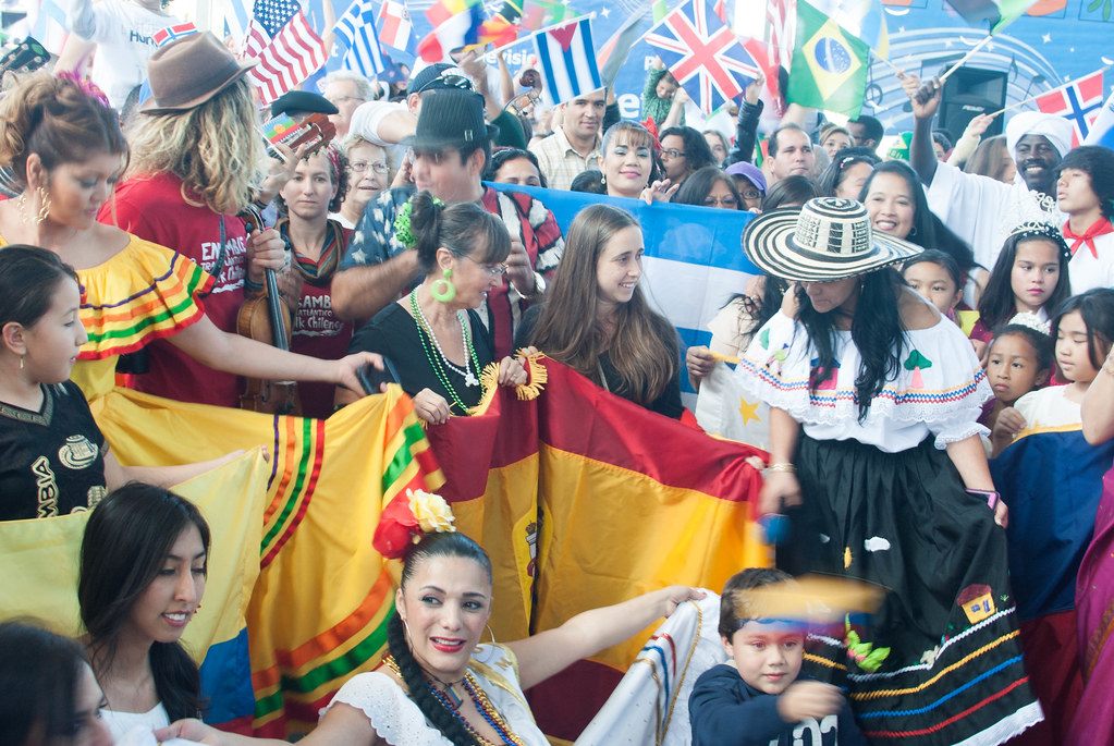 A smiling crowd in traditional dress waves Latin American and world flags at CultureFest 2014 at the Chattanooga Market