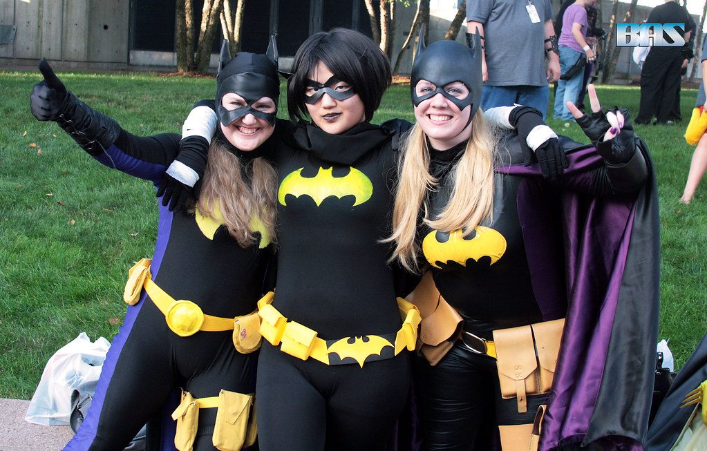 Three smiling fans in Batgirl costumes posing on a lawn at ConnectiCon 2013 in Hartford