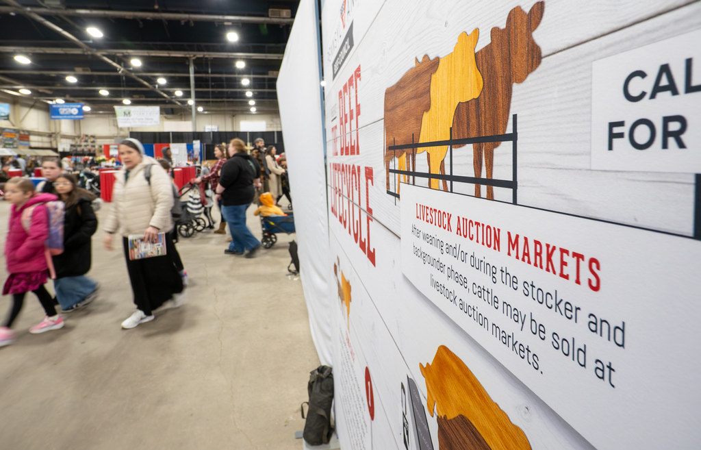Families with strollers walking past a beef lifecycle exhibit wall at the 2026 Pennsylvania Farm Show