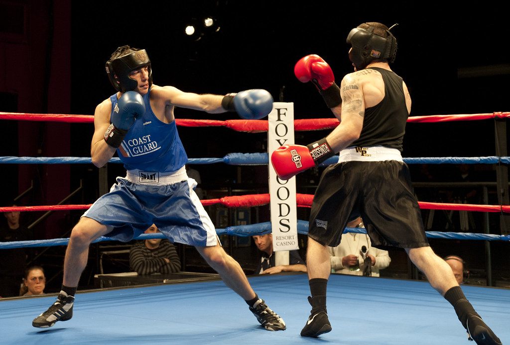A Coast Guard boxer throws a jab at the 2013 NCBA collegiate boxing championship finals, with a Foxwoods-branded ring corner