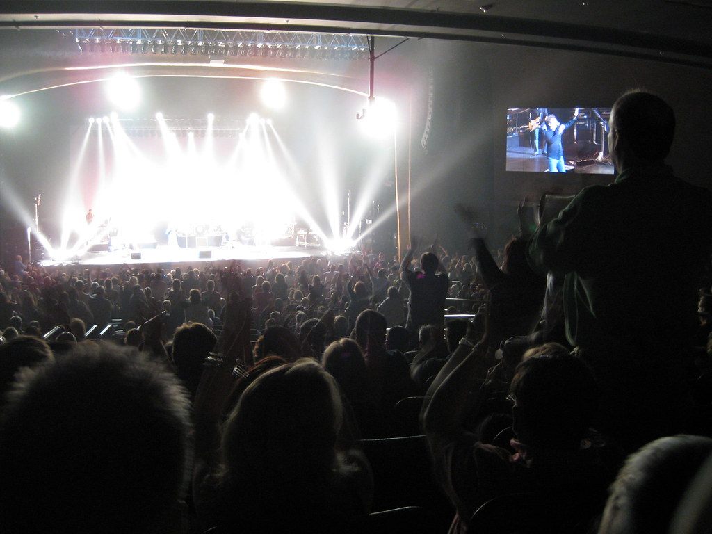 A packed theater audience on its feet, cheering toward a stage washed in white spotlights at the MGM Grand Theater at Foxwoods, 2009