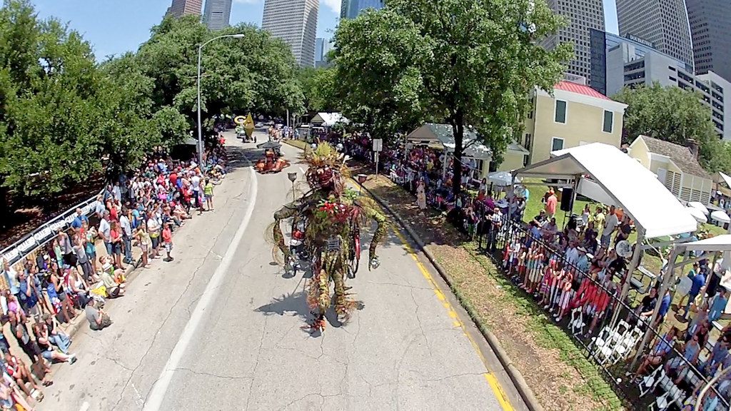 Crowds line a tree-shaded downtown Houston street as a costumed art-car entry rolls past during the 2012 Art Car Parade