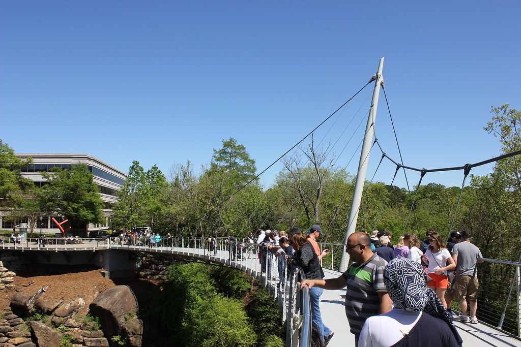 Visitors crowding the curved Liberty Bridge suspension walkway above the Reedy River gorge in Falls Park, downtown Greenville