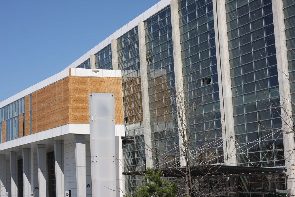 Tall glass curtain walls and a stone-clad section of a Georgia World Congress Center building under a clear blue sky