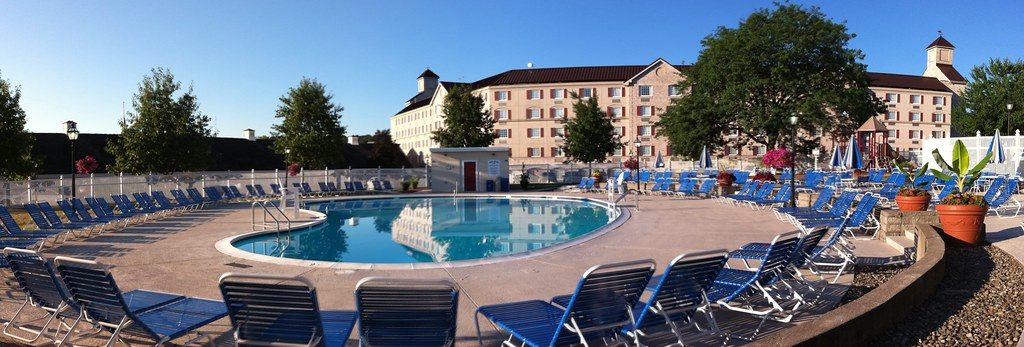 Panorama of the Hershey Lodge outdoor pool ringed by blue loungers, with the guest-room wings behind