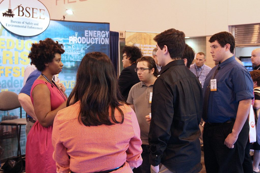 Visitors with badges crowd around a federal offshore-safety agency's booth on the Offshore Technology Conference show floor