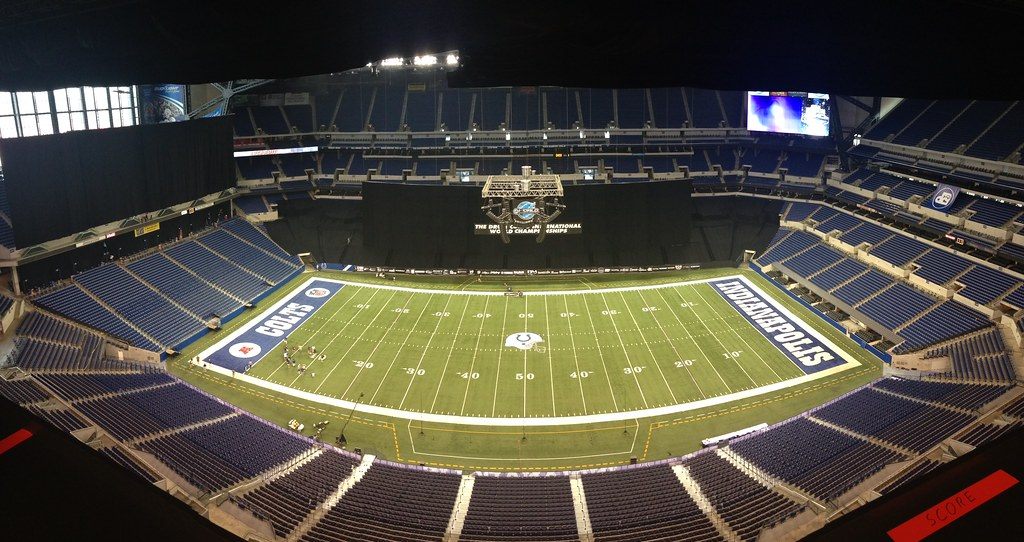 The inside of Lucas Oil Stadium from the upper deck, with the field, blue seating bowl and roof