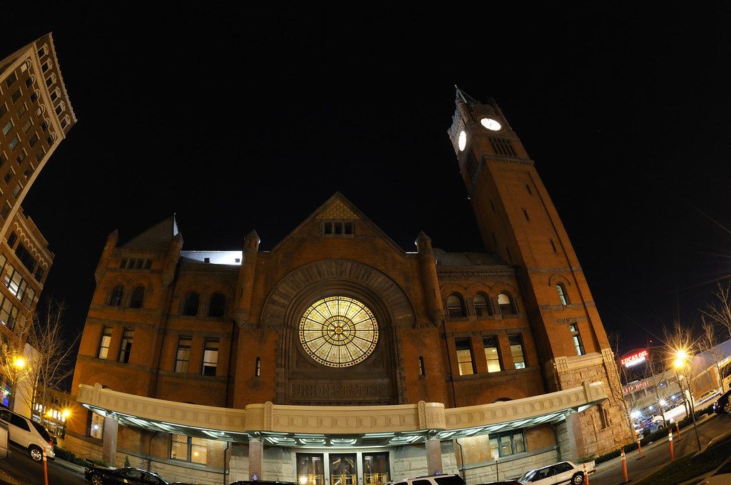 The red-brick Romanesque Union Station in Indianapolis with its clock tower and round window, lit at night