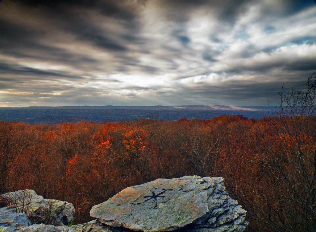 Autumn view from the rocks on Camelback Mountain over orange woods to the valley below, under a streaked grey sky