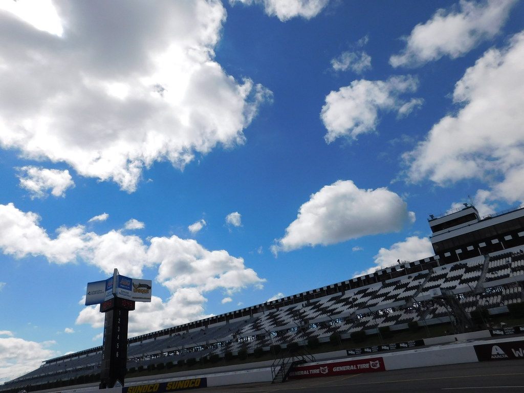 The empty main grandstand and scoring tower at Pocono Raceway under a blue sky with big clouds