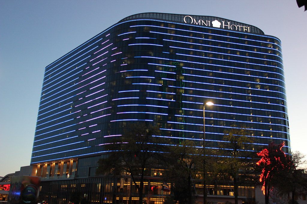 The Omni Dallas Hotel at dusk, its curved facade striped with LED light bands