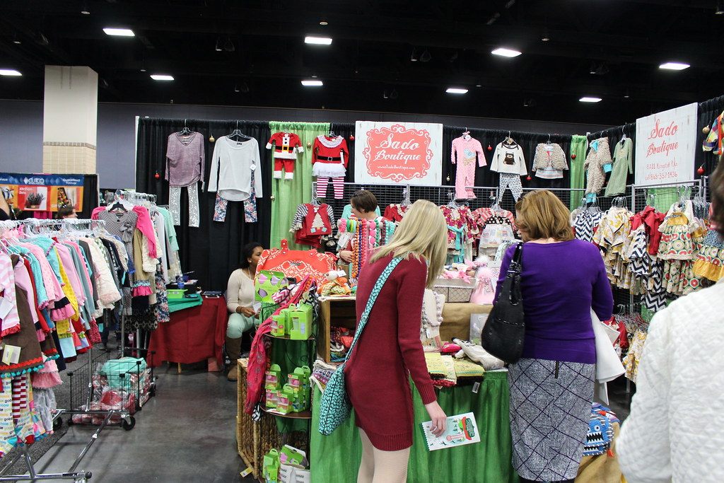 Shoppers browse a children's boutique booth hung with holiday outfits at Tinsel and Treasure 2014, the Junior League of Knoxville's holiday market