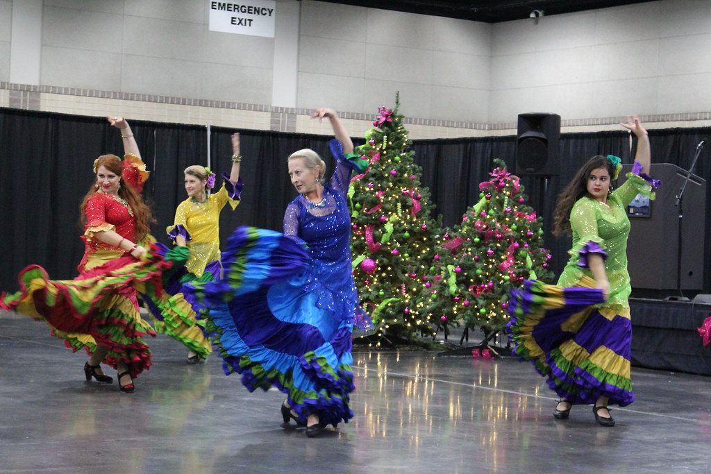 Dancers in swirling ruffled skirts perform in front of decorated Christmas trees at Tinsel and Treasure 2014 in Knoxville