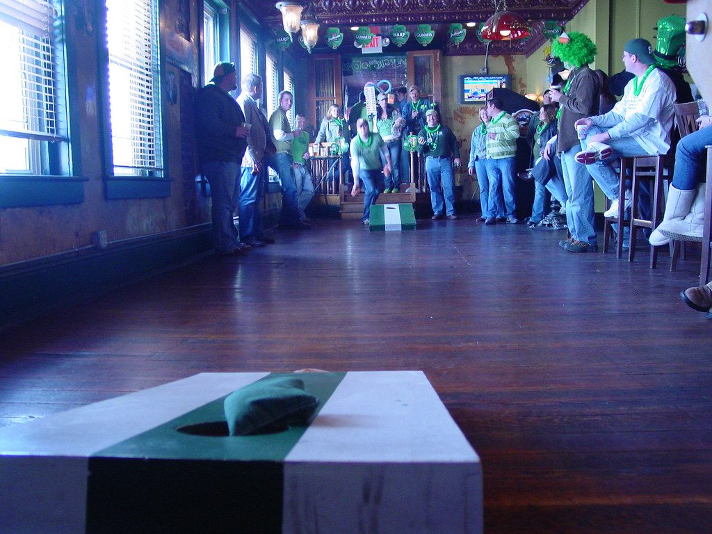A St. Patrick's Day crowd in green watches a cornhole game down the plank floor of McCoul's Public House in downtown Greensboro