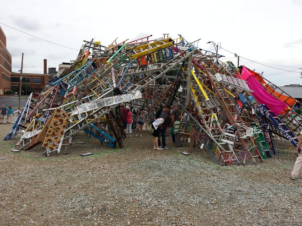 Festival-goers walk under Charlie Brouwer's Rise Together, a dome of hundreds of painted ladders, during the National Folk Festival in downtown Greensboro