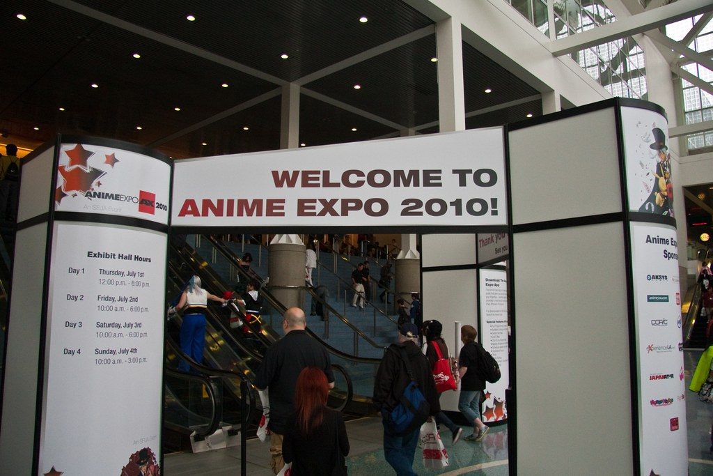 Attendees pass a Welcome to Anime Expo 2010 arch toward the escalators inside the Los Angeles Convention Center