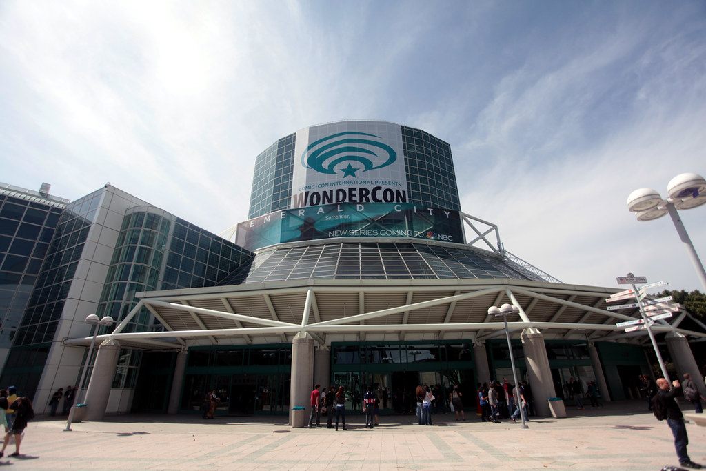 Attendees outside the Los Angeles Convention Center's glass entrance pavilion under a WonderCon banner in 2016