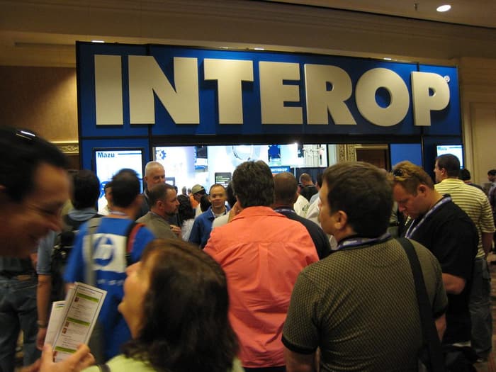 Badge-wearing attendees crowding toward the big blue INTEROP entrance sign at Interop Las Vegas 2008