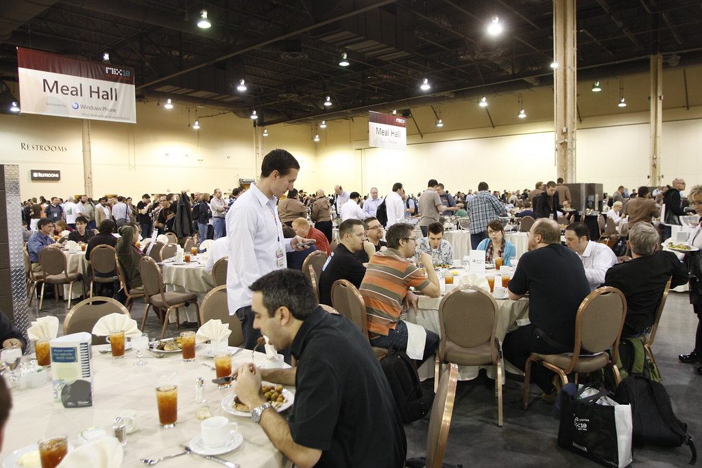 Hundreds of MIX10 attendees eating lunch at round tables under a Meal Hall banner in a Mandalay Bay exhibit hall