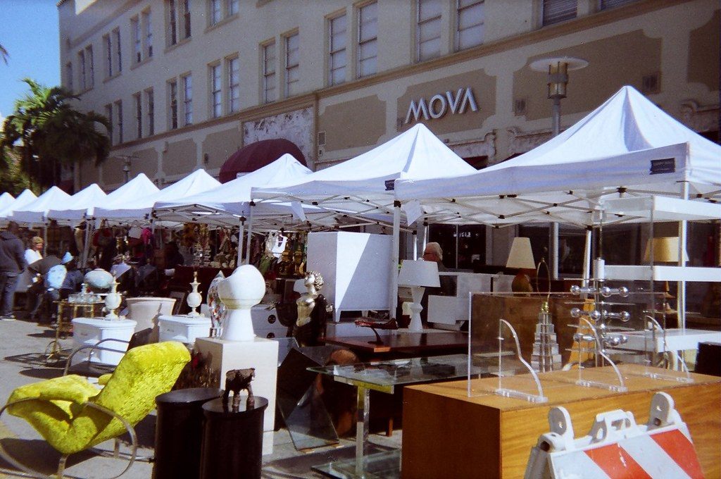 Mid-century furniture and lamps for sale under white tents at the antique show on Lincoln Road Mall