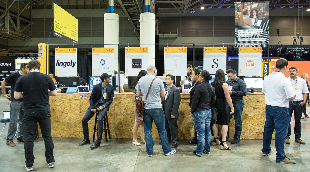 Attendees crowd startup booths with numbered signs on a concrete exhibit floor at the Collision conference in New Orleans