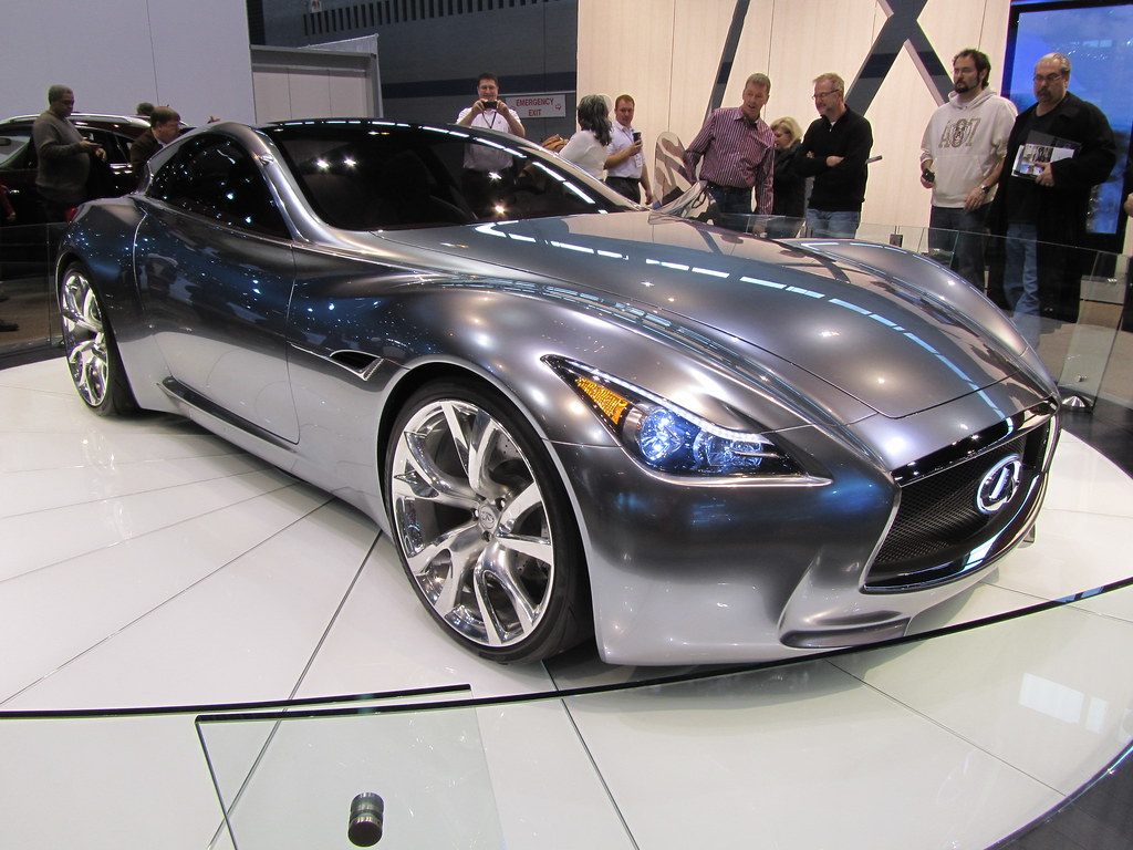 Visitors photographing a silver Infiniti concept coupe on a white turntable at the 2011 Chicago Auto Show