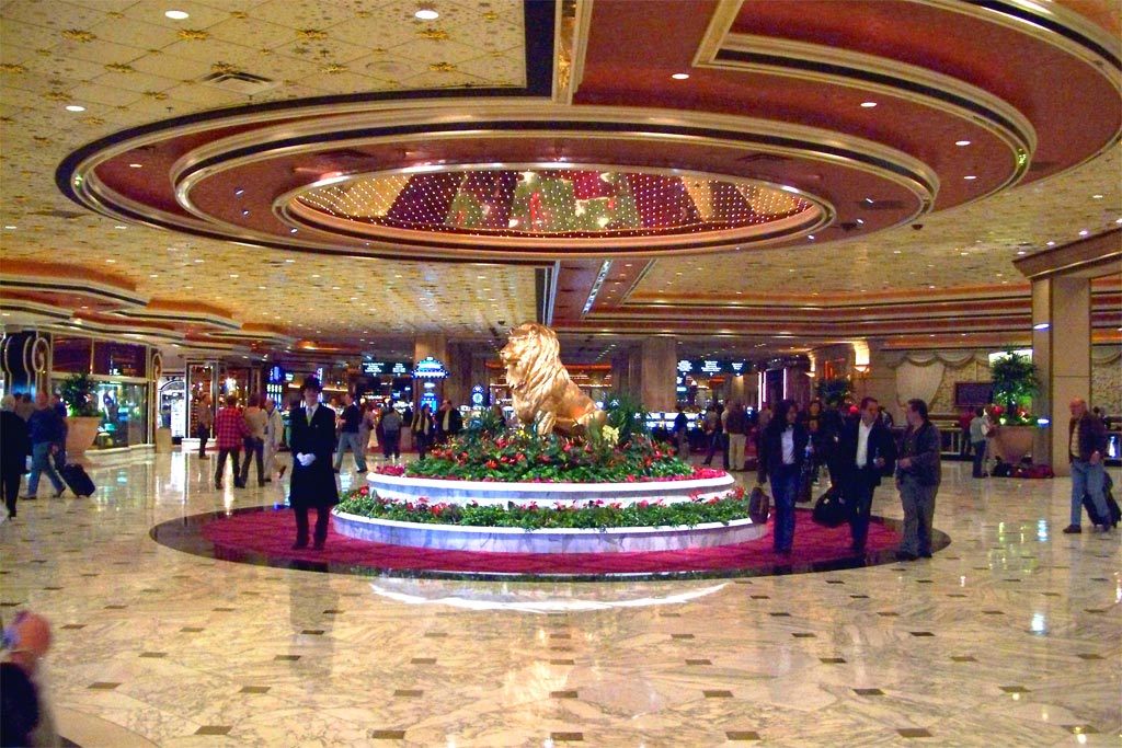 Guests with luggage pass the golden lion statue under the domed ceiling of the MGM Grand lobby, Las Vegas