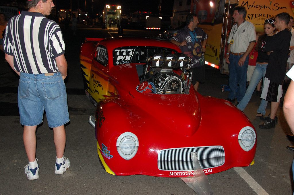 Visitors looking over a red Mohegan Sun funny car at a jet-car night event