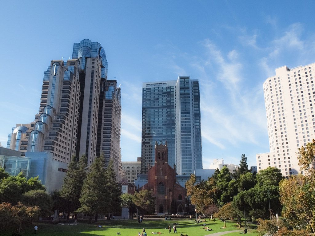 People relaxing on the lawn of Yerba Buena Gardens with St. Patrick's Church, the Marriott Marquis and downtown towers behind