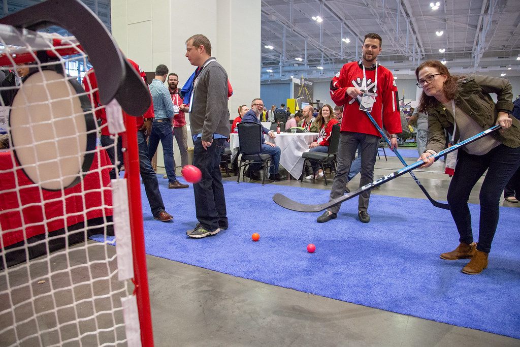 Attendees playing a street-hockey booth game on the DrupalCon Nashville 2018 exhibit floor