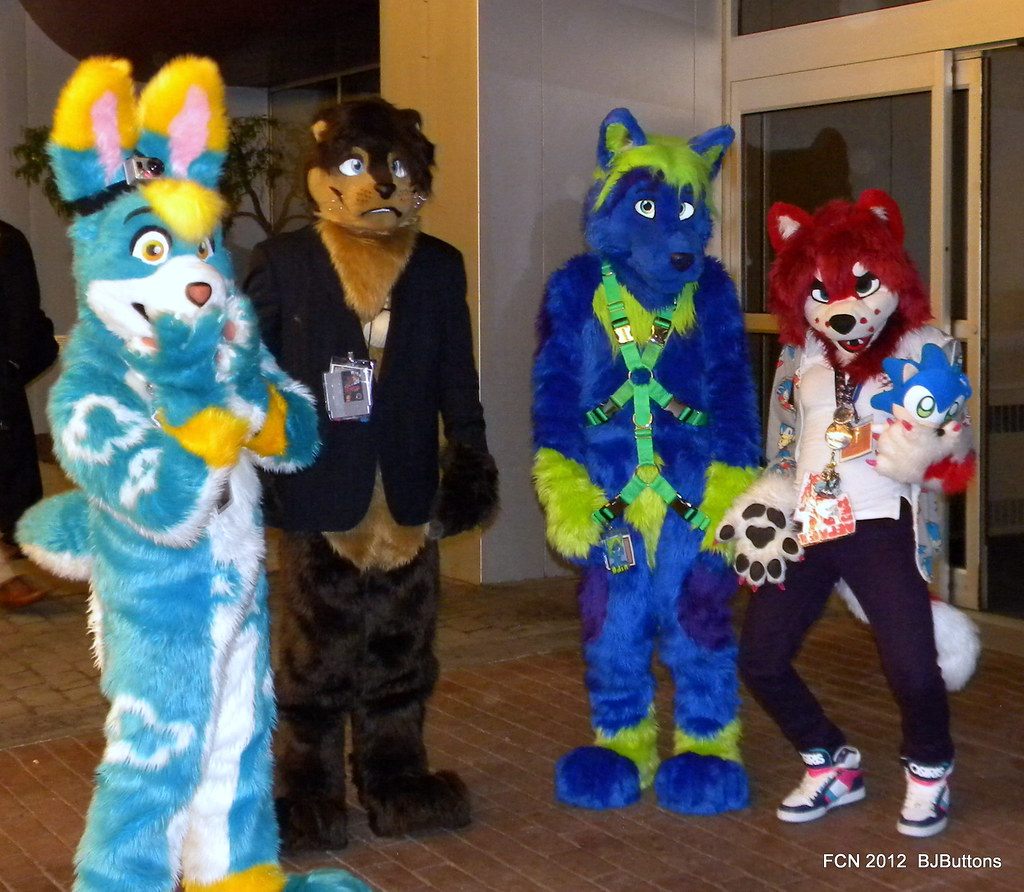 Four fursuiters in blue, brown and red costumes pose outside a hotel entrance at Furry Connection North 2012 in Novi